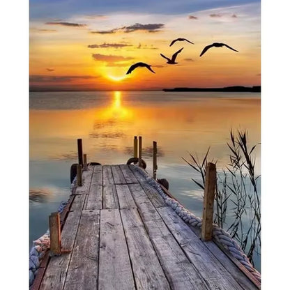 Paint by numbers kit of a wooden dock stretching into calm water at golden sunset with birds flying overhead, 30x40cm